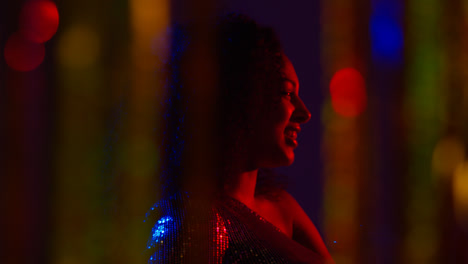 Young-Woman-Having-Fun-In-Nightclub-Or-Bar-Shot-Through-Tinsel-Curtain-in-Foreground